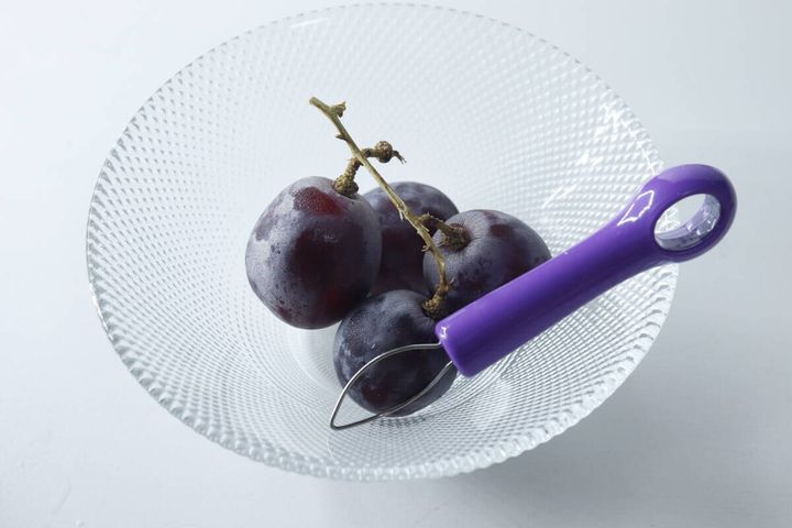 ガラスの器に入ったぶどうと紫色の皮むき器
