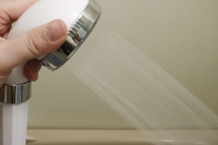 手で持ったシャワーヘッドからストレートモードで水が出ている