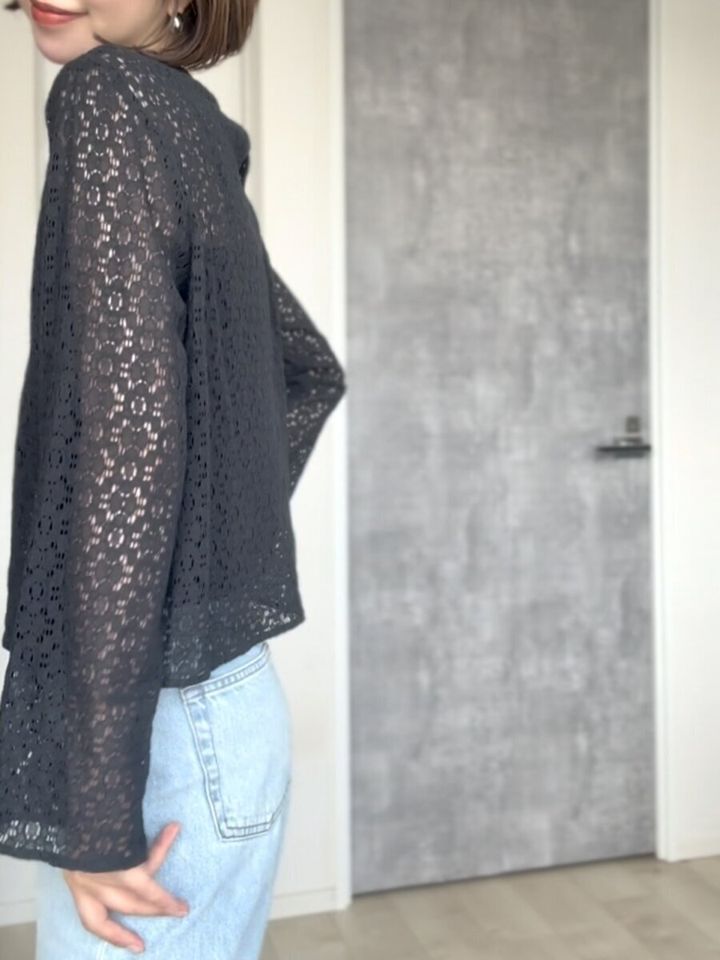 黒いレースブラウスとデニムを着用した女性の横向き