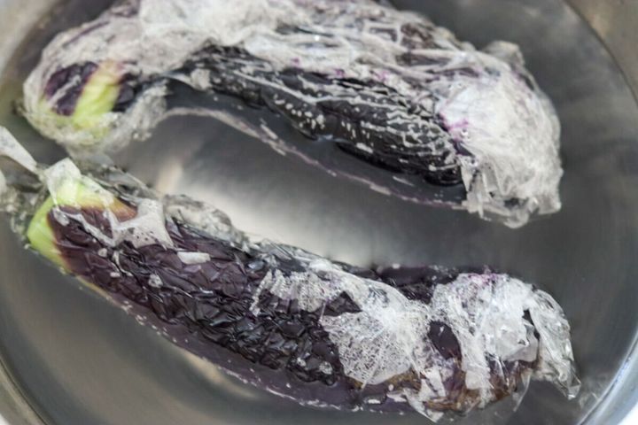 冷水に浸され、しわが寄ったラップに包まれた加熱後のなす