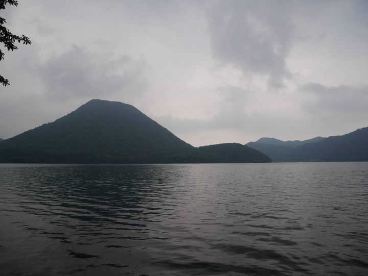湖の向こうに山並みが広がる、静かな水辺の風景