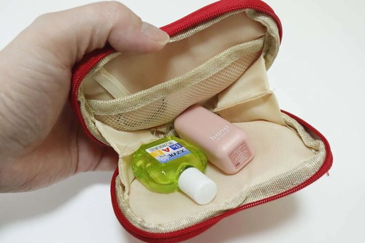 赤いハート型小物入れの中にリップと目薬が入っている