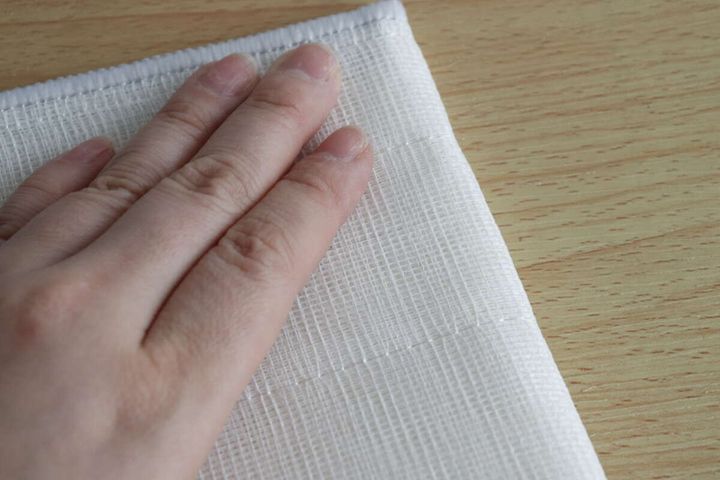 木目のテーブルに広げたふきんに手を置いている