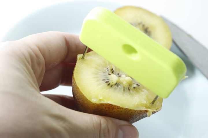 キウイの断面に皮むき器の細い針が刺さっている手元