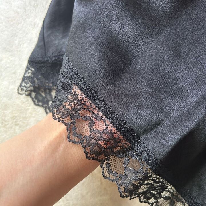 黒いサテンキャミソールの裾レースを指で触れている様子