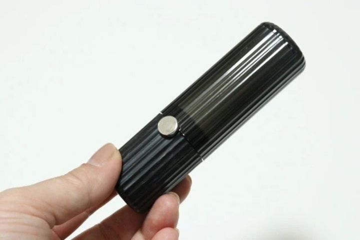 右手が黒いリップのような形状の粘着クリーナーを握っている