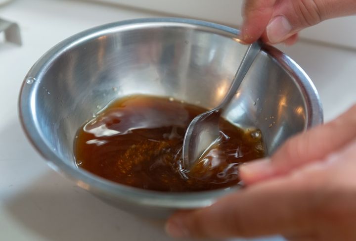 ボウルに入れた調味料をスプーンで混ぜる風景 ソースやタレ、ドレッシングを手作りする家庭料理のシーン 
