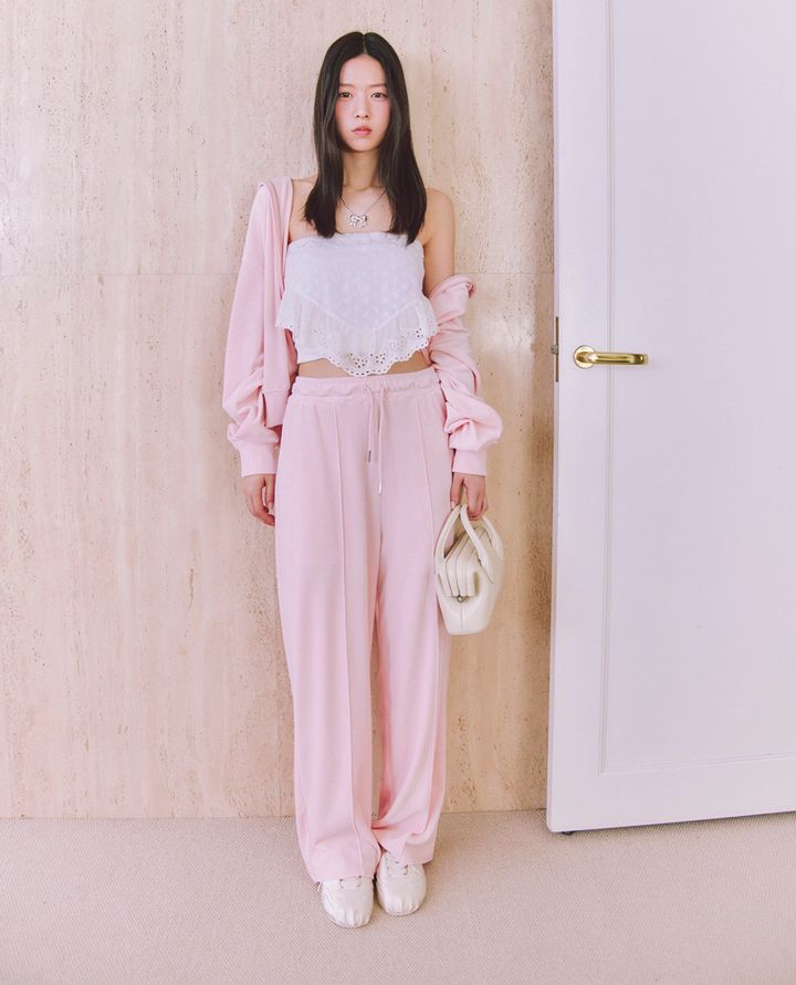 TWICEモモの着こなしにインスパイアされた、片山友希の大人の「空港セットアップ」コーデ。ピンクのジップパーカーをずるっと肩見せさせてヘルシーに羽織り、白のレースビスチェとピンクのワイドスウェットパンツを合わせた可愛い肌見せスタイル。