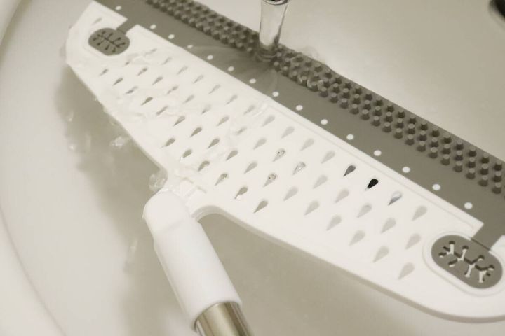 ワイパーほうきのヘッド部分を水で洗い流している様子。