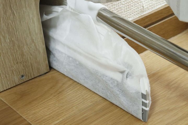 お掃除シートを付けたワイパーほうきで家具の隙間を掃除している。