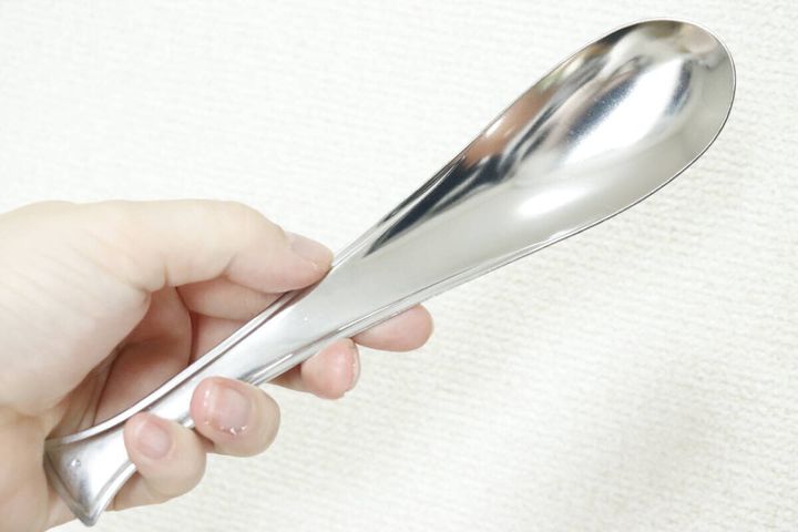 レンゲスプーンを握る女性の手のアップ