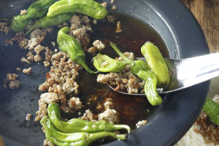 ひき肉とピーマンの炒め物をレンゲスプーンですくう様子