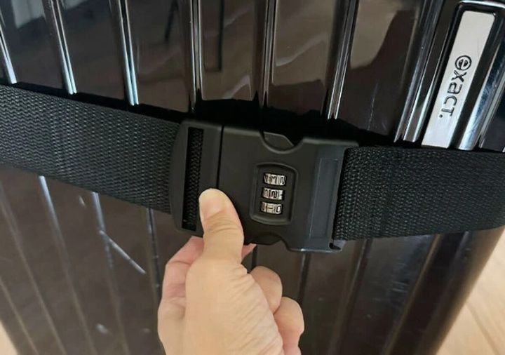 スーツケースに装着されたダイヤルロック付きベルトを指で触っている