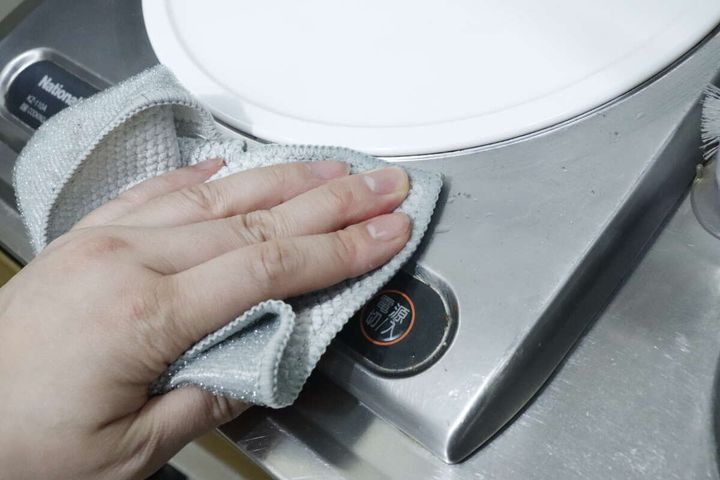 手が「凄腕くんお助けクロス」でコンロの細かい部分を拭いている