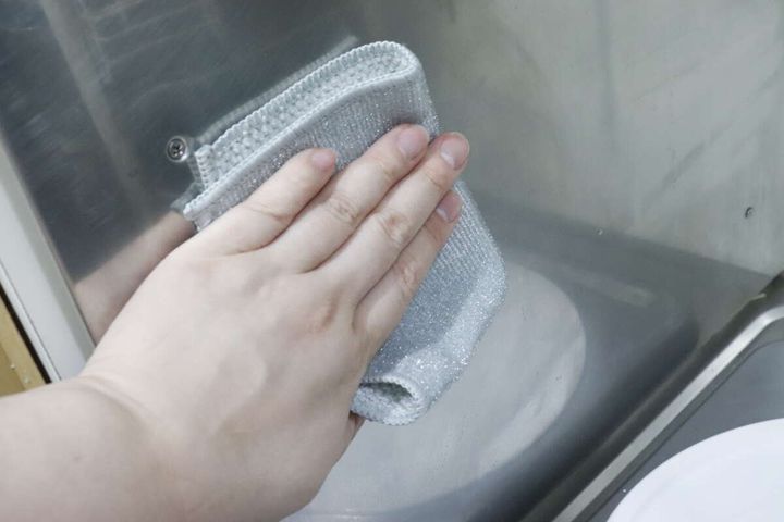 手が「凄腕くんお助けクロス」のループ繊維面でステンレス壁面を拭いている