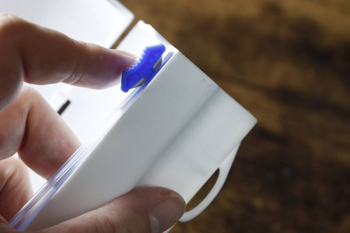 まな板シートケースのスライドカッターの青い部分を指で操作している様子