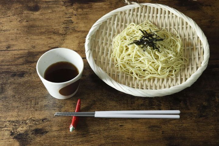 盆ざるに盛り付けられた冷やし中華と、つゆ、箸が並ぶ食卓