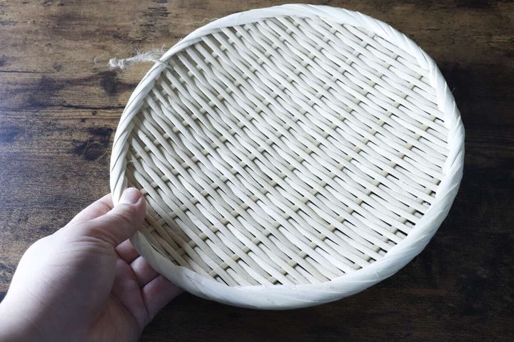 男性が盆ざるを片手で持っている様子、サイズ感がわかる