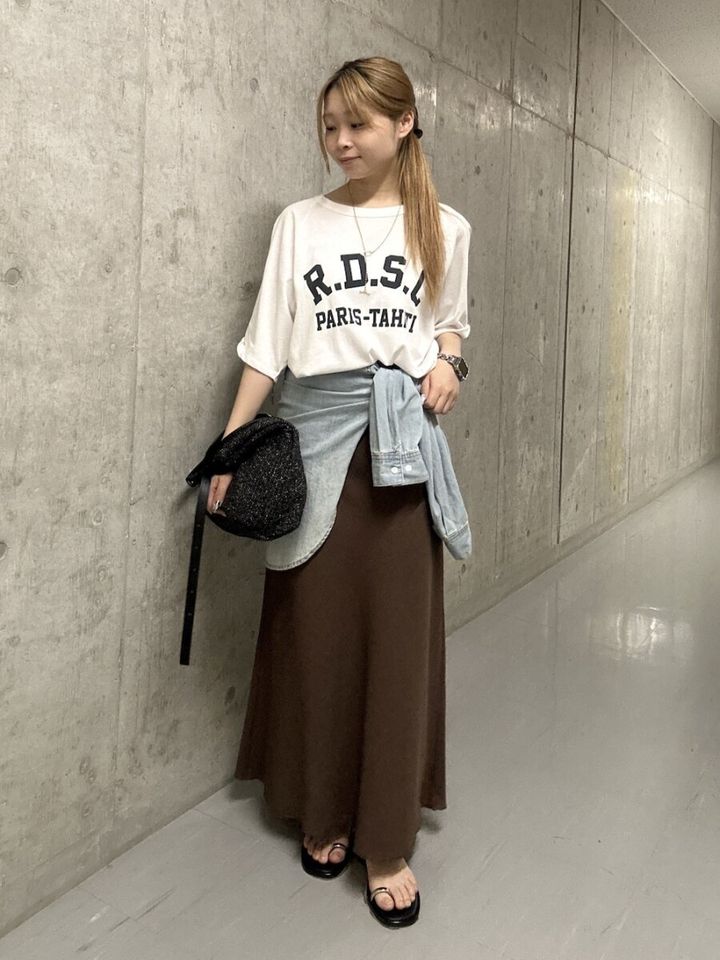 ロゴTとブラウンロングスカート、デニムシャツを巻いた女性