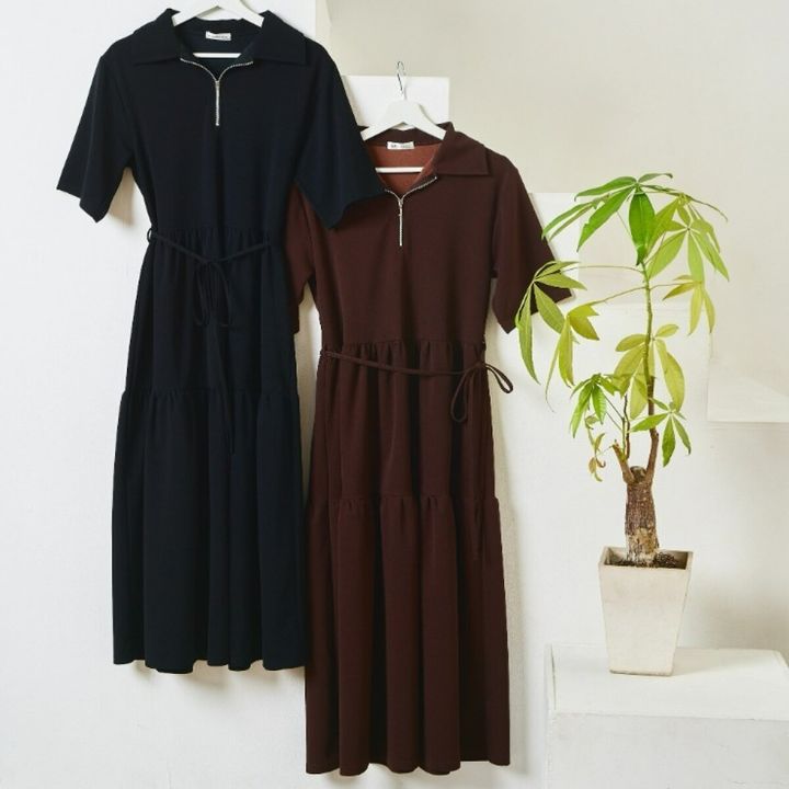 黒と茶色のハーフジップワンピースが2着、観葉植物の横に吊るされている