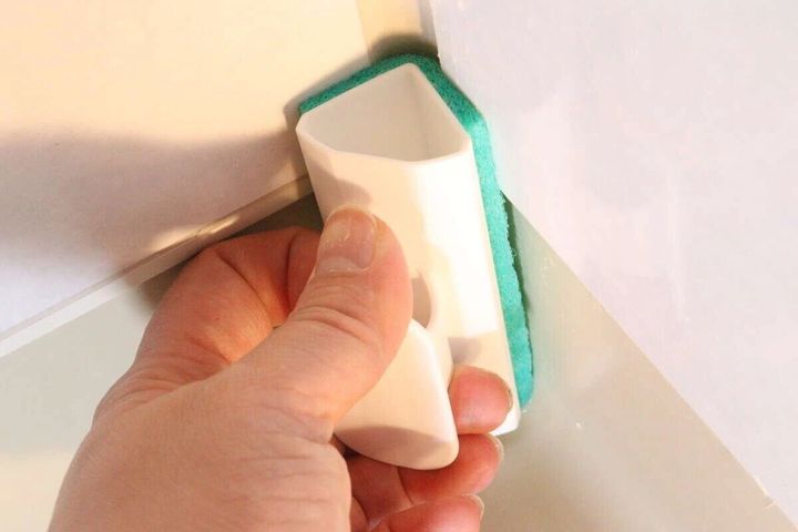 手で浴室ブラシを使い浴室の壁の角を掃除している様子