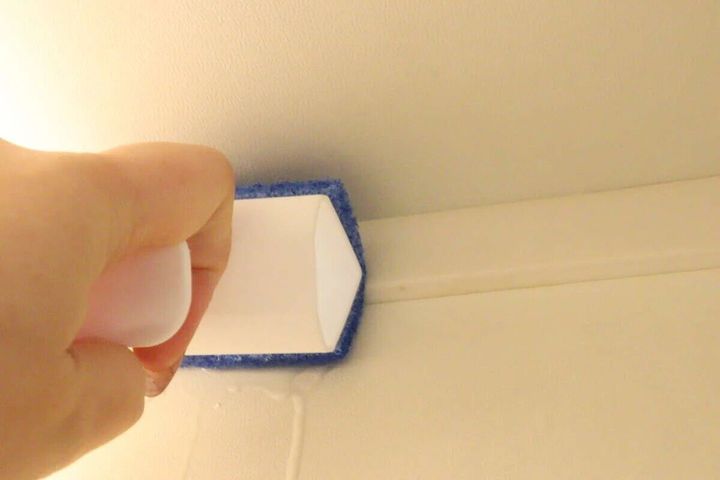 手で浴室ブラシを使い浴室の床と壁の境目を掃除している様子
