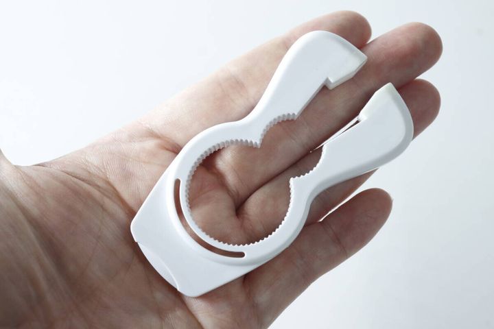手のひらに乗せた白い4WAYキャップオープナー。商品のサイズ感がわかる