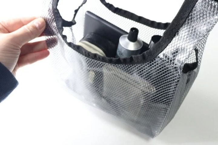 手が黒いビニールバッグの口を開け中身を見せている様子