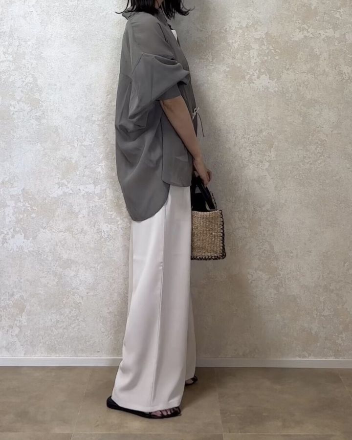 オリーブ色のシアーシャツと淡色ワイドパンツを着用した女性の横姿