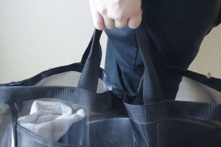 女性が黒いメッシュトートバッグの持ち手を掴んでいる