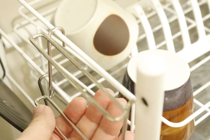 白い水切りラックにステンレス製の包丁ホルダーを設置している手元