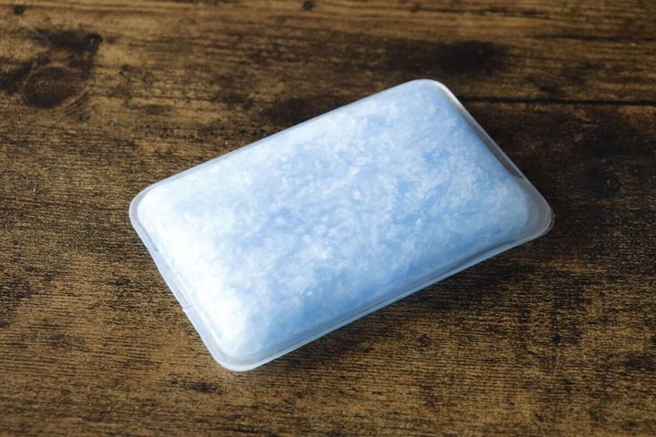 青く凍結した状態のスマホ冷却パッド本体が木目のテーブルに置かれている