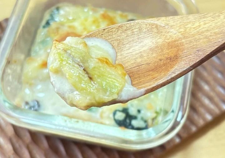 木のレンゲスプーンで熱々のグラタンをすくっている様子
