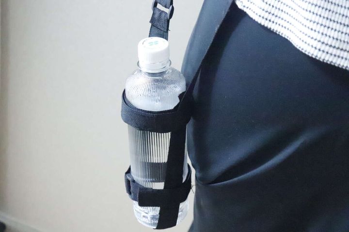 女性がボトルホルダーを肩から下げてペットボトルを携帯している