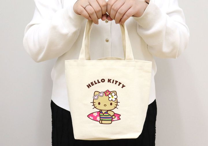 白い服の女性がハローキティのミニトートバッグを手に持っている