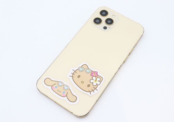 スマートフォンの背面にキティとシナモロールのステッカーが貼られている