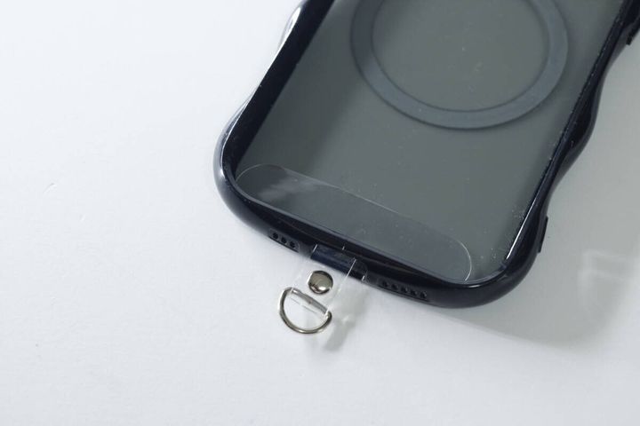 黒いスマホケースの充電口に透明なストラップシートを挟み込んだ状態