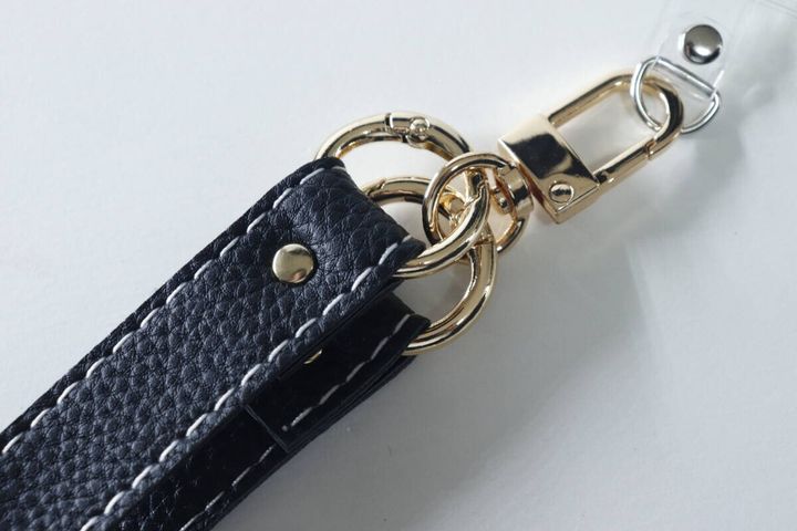 ゴールドの金具とリングで繋がれた黒い合皮のスマホストラップ