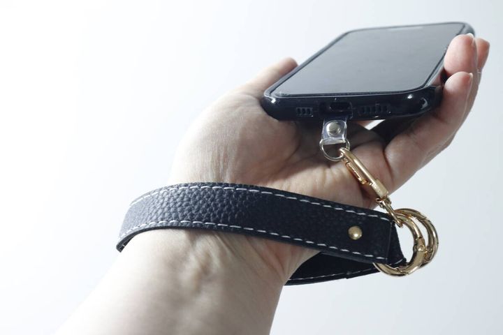 女性が黒いスマホストラップを手首に通してスマホを持っている様子