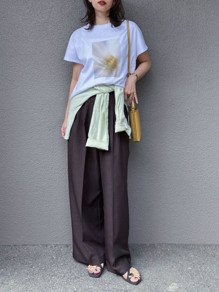 フォト白Tに黒ワイドパンツ、腰にグリーンのシャツを巻いた女性