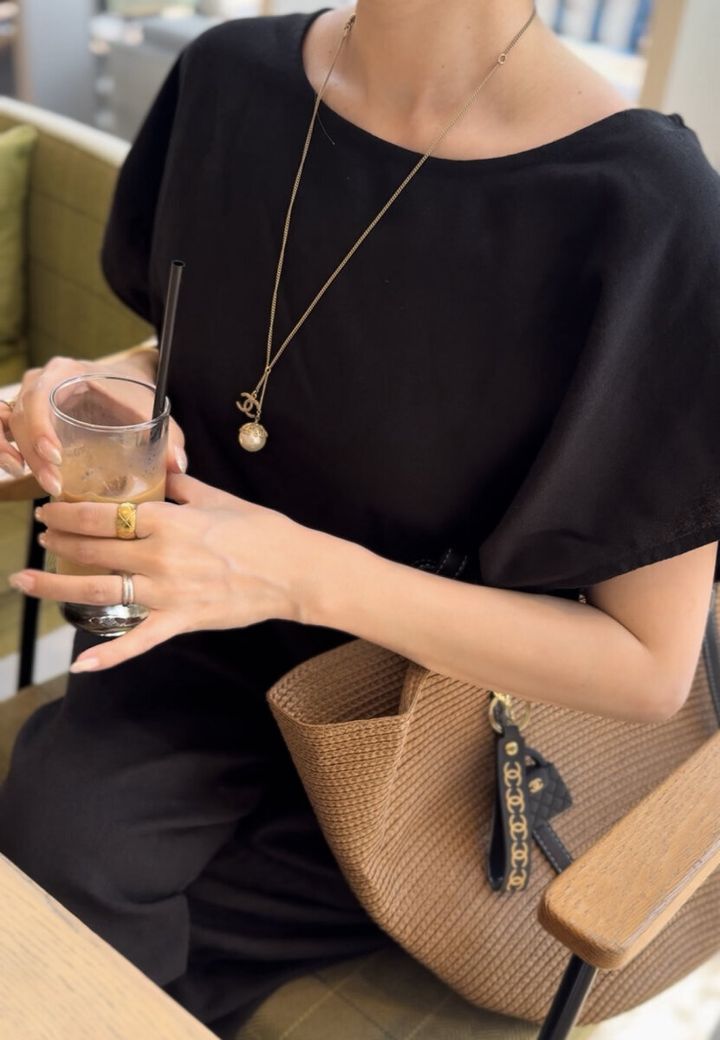 カフェでアイスコーヒーを飲む女性の手元とネックレス