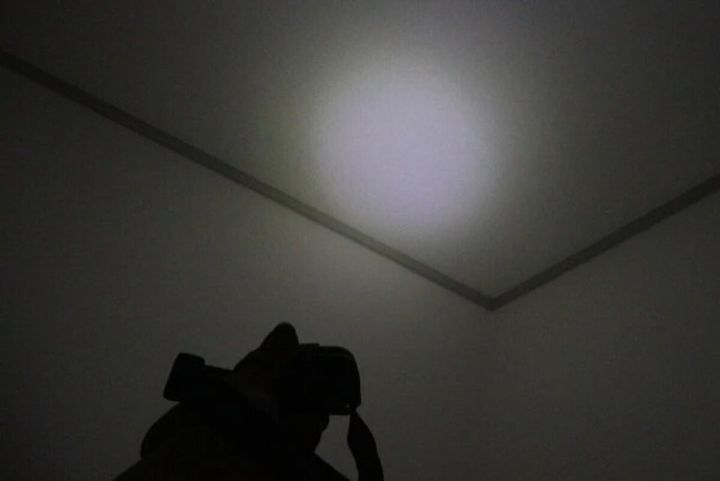 頭にヘッドライトを装着した人物が暗い部屋の天井を照らしている