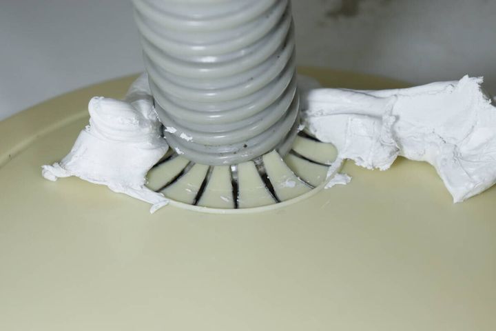 洗濯機の排水ホースと床の隙間に白いすきまパテを充填した直後の状態