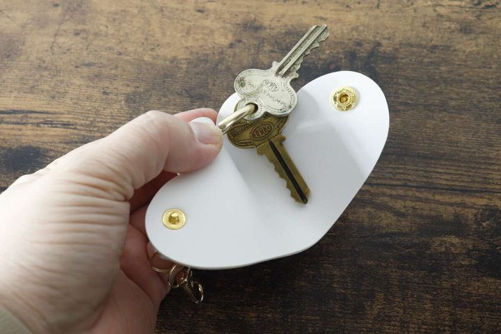 手が白いキーカバーを開き、中に鍵が2本取り付けられている