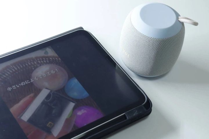 タブレットの横に置かれたライトブルーのBluetoothスピーカー