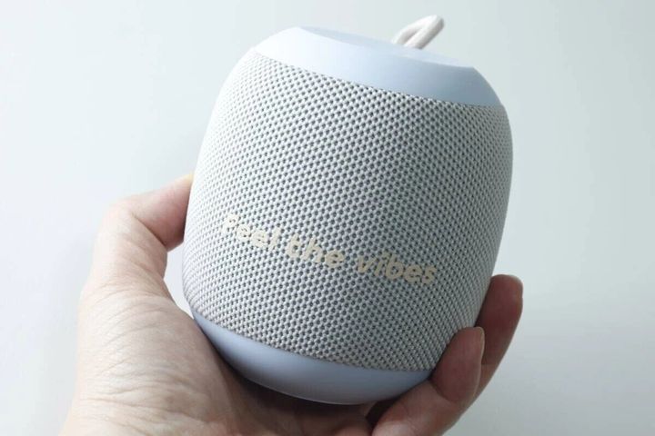 手のひらに乗せられた丸いライトブルーのBluetoothスピーカー