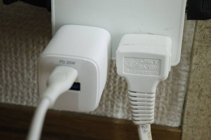 白いGaN USB充電器がコンセントに差し込まれ、隣のプラグと干渉しない様子