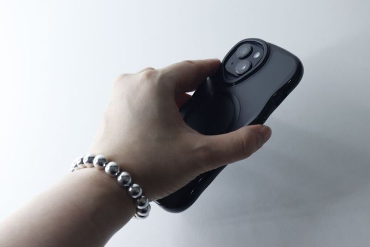 手首にブレスレットストラップをつけスマホを持つ女性