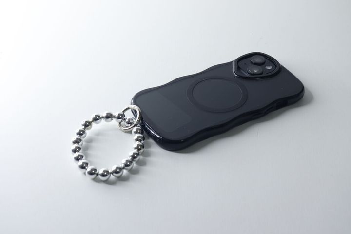 黒いスマホケースにシルバーのブレスレットストラップを装着