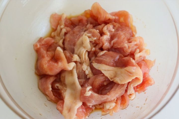 透明なボウルに入った豚こま切れ肉に片栗粉と調味料が絡められている様子